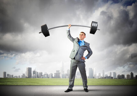 Image of strong businessman lifting barbell above head with one handの写真素材