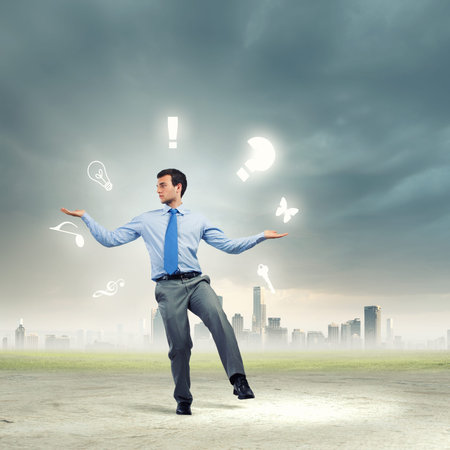Young businessman juggling with conceptual symbols against city backgroundの写真素材