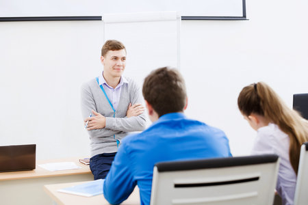 Young teacher in classroom standing in front of class