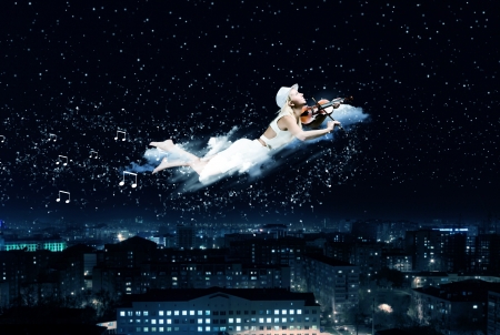 Young blond girl flying in night skyの写真素材