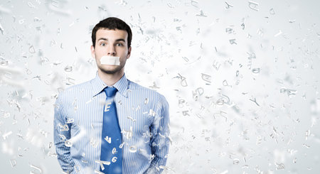 Young handsome businessman with adhesive tape on mouthの写真素材