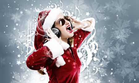 Young attractive Santa girl listening music in headphonesの写真素材