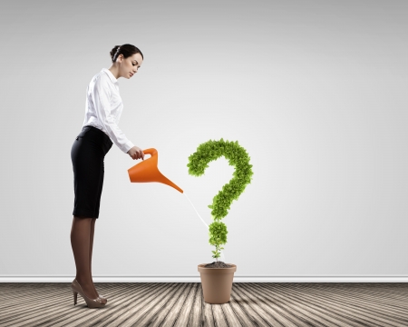 Young attractive businesswoman watering plant in pot with canの写真素材