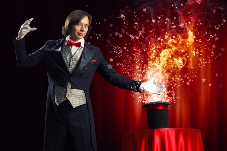 Image of magician holding hat with lights and fumes going outの写真素材