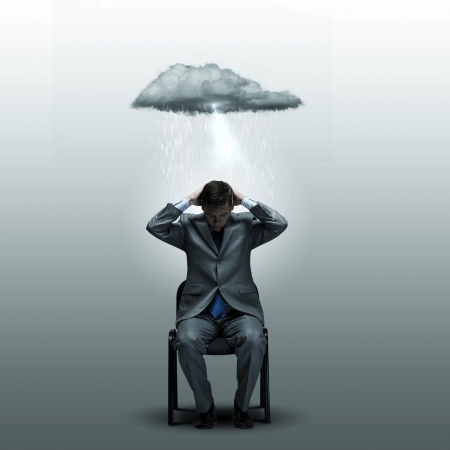 Young businessman sitting on chair with suitcase on kneesの写真素材