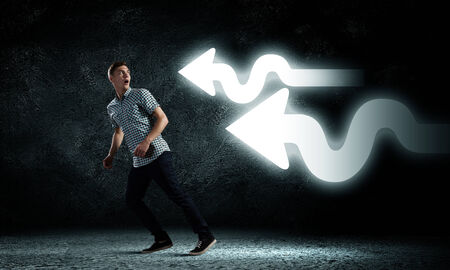 Young funny man ruining away from arrowsの写真素材