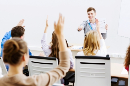 Young teacher in classroom standing in front of classの写真素材