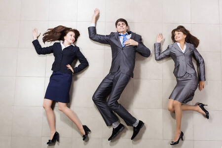 Young people in business suits lying on floorの写真素材