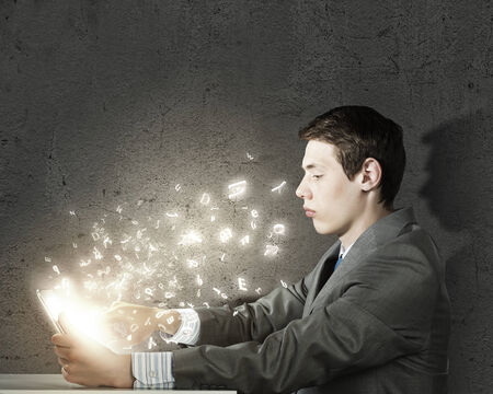 Young man sitting at table and using laptopの写真素材