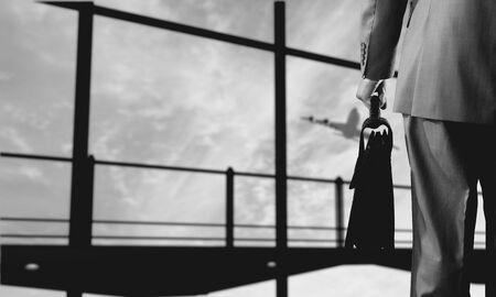 Back view of businessman at airport with suitcase in handの写真素材