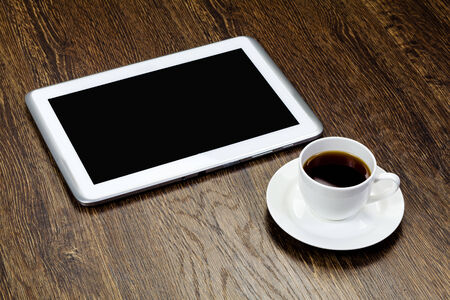 Tablet pc cup of coffee and notepad at tableの写真素材