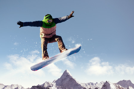 Snowboarder making jump high in clear skyの写真素材
