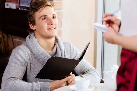 Young attractive woman making order at restaurantの写真素材