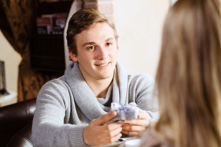 Young man at date giving box with present to his girlの写真素材