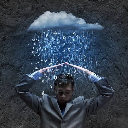 Businessman sitting under rain protecting head with armsの写真素材