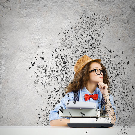 Young funny woman in glasses using typewriterの写真素材