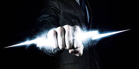 Businessman holding lightning in fist  Power and controlの写真素材