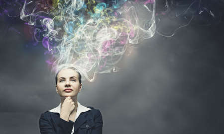 Thoughtful businesswoman with colorful fumes above headの写真素材