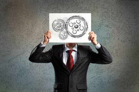 Businessman hiding his face behind paper with drawingの写真素材