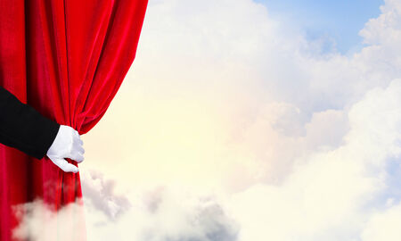 Hand of businessman opening red velvet curtainの写真素材