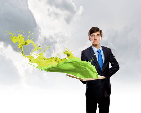 Handsome businessman holding frame with colorful splashesの写真素材