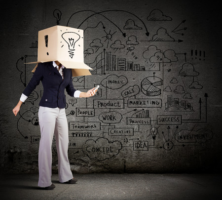 Businesswoman using mobile phone wearing carton box on headの写真素材