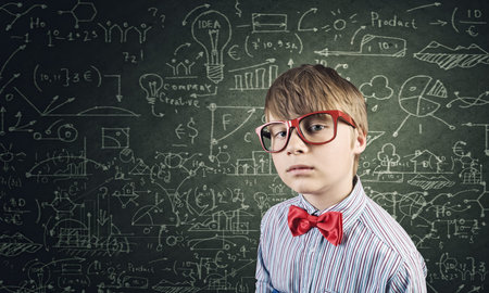 Genius boy in red glasses near blackboard with formulas