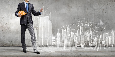 Young man engineer in helmet drawing construction projectの写真素材