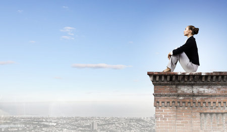 Young attractive lady sitting on top of building