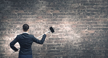 Young attractive businesswoman with hammer in handsの写真素材