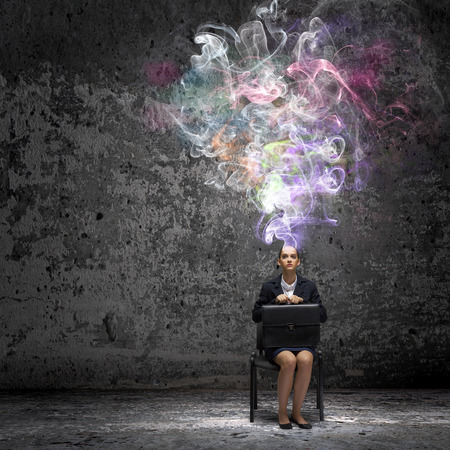 Young thoughtful confused businesswoman sitting on chairの写真素材