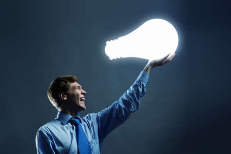 Businessman holding huge electrical bulb in handの写真素材