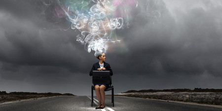 Young thoughtful confused businesswoman sitting on chairの写真素材