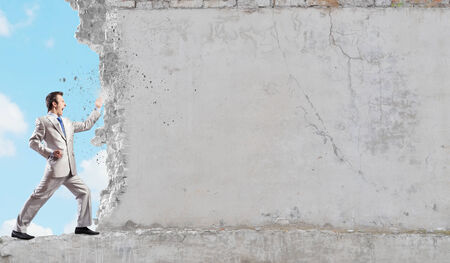Businessman breaking stone wall with karate punchの写真素材