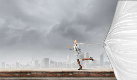 Young businesswoman running and pulling white blank bannerの写真素材