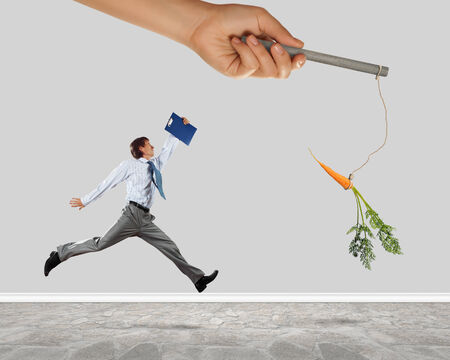 Funny image of businessman chased with carrotの写真素材