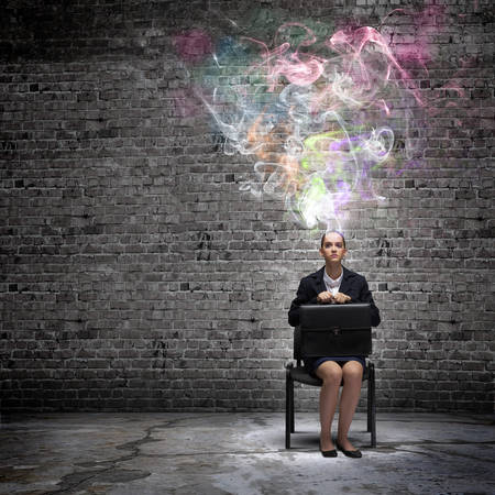 Young thoughtful confused businesswoman sitting on chairの写真素材