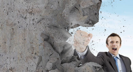 Businessman breaking stone wall with karate punchの写真素材