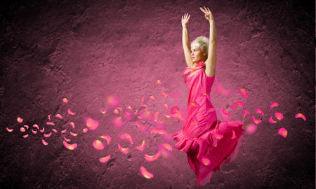 Young attractive woman in pink dress jumping highの写真素材