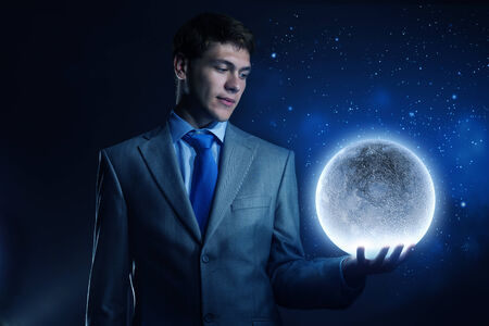 Young man in suit holding moon in palmの写真素材