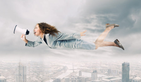Young businesswoman with megaphone flying high in sky