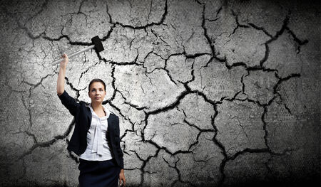 Young attractive businesswoman with hammer in handsの写真素材
