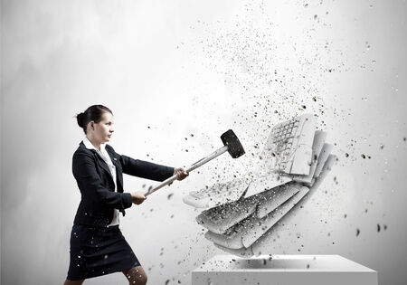 Businesswoman in anger crashing keyboard with hammerの写真素材