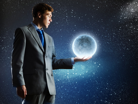 Young man in suit holding moon in palmの写真素材