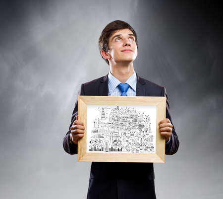 Handsome businessman holding frame with business sketchesの写真素材