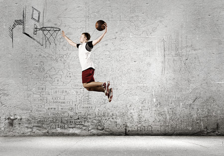 Young man basketball player throwing ball in basketの写真素材