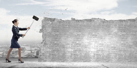 Young attractive businesswoman with hammer in handsの写真素材