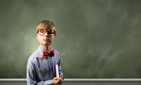 Genius boy in red glasses near blackboard with formulasの写真素材