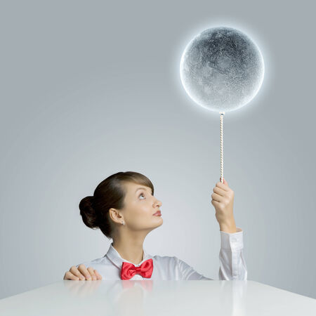 Young woman holding balloon colored like moon planetの写真素材