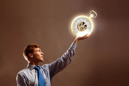 Young businessman holding pocket watch in hand